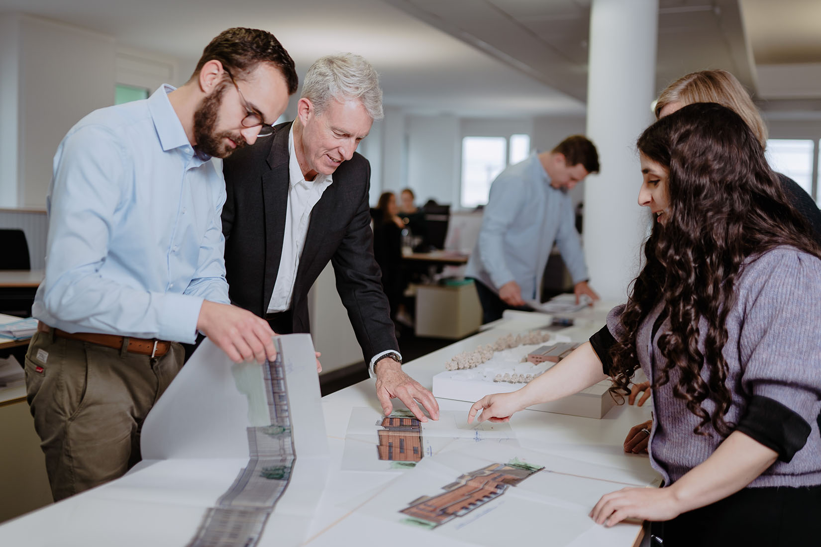 People are leaning over and discussing a model of a building