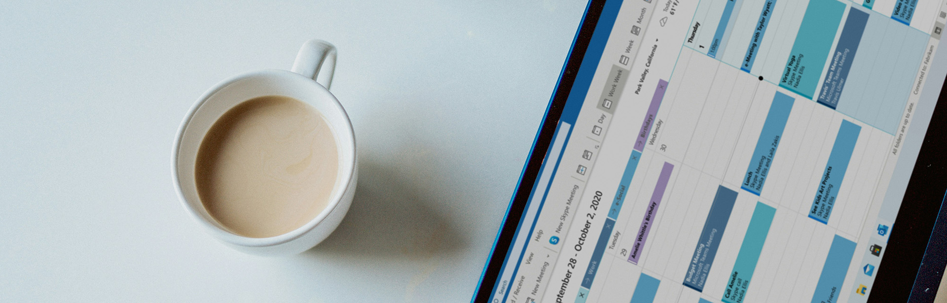A steaming cup of coffee is positioned next to a laptop screen filled with a vibrant calendar, indicating a busy week ahead.