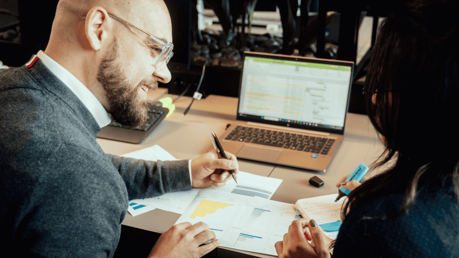 Zwei Kollegen sitzen an einem Schreibtisch und arbeiten gemeinsam an einem Projekt
