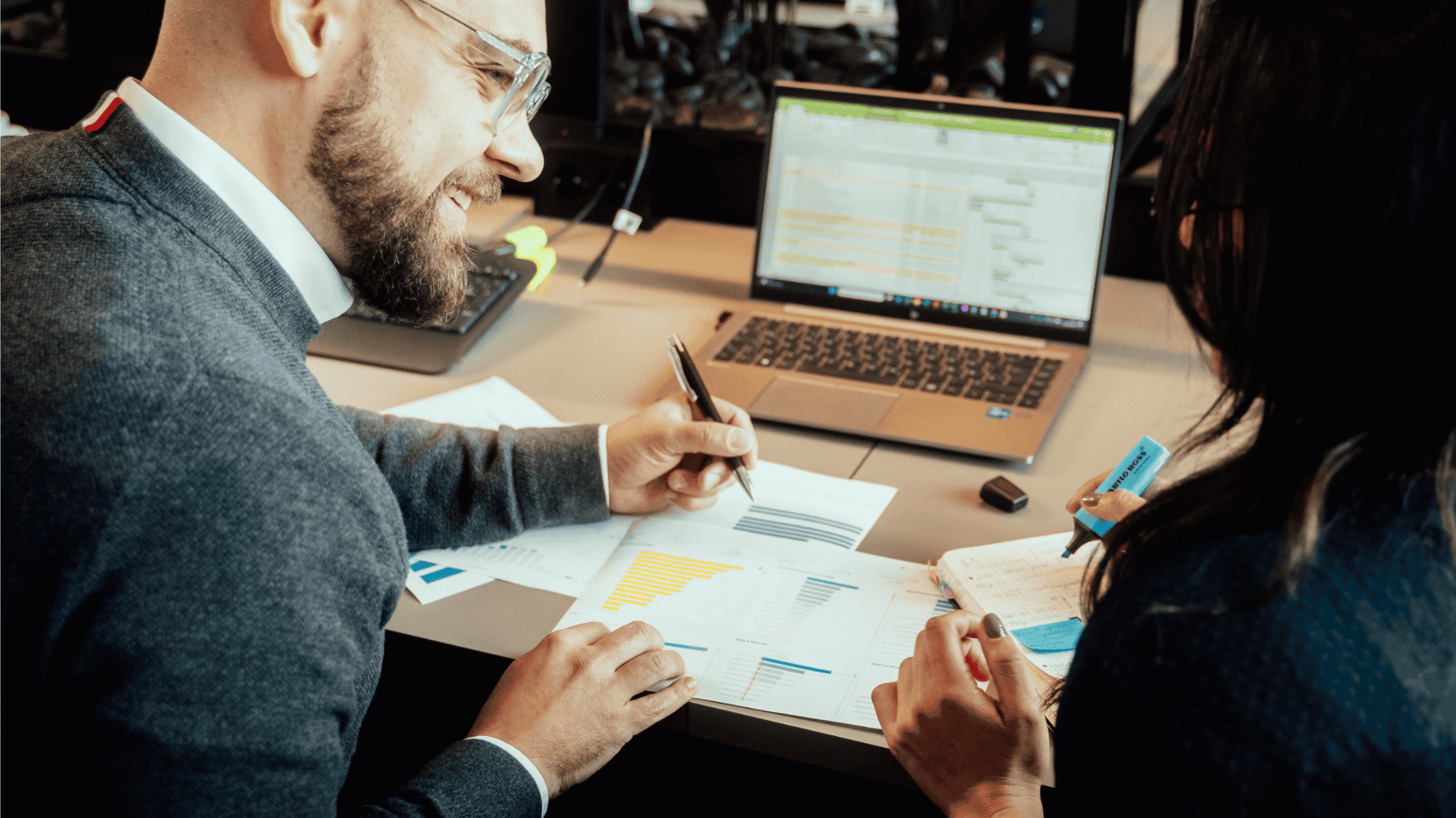 Zwei Kollegen sitzen an einem Schreibtisch und arbeiten gemeinsam an einem Projekt