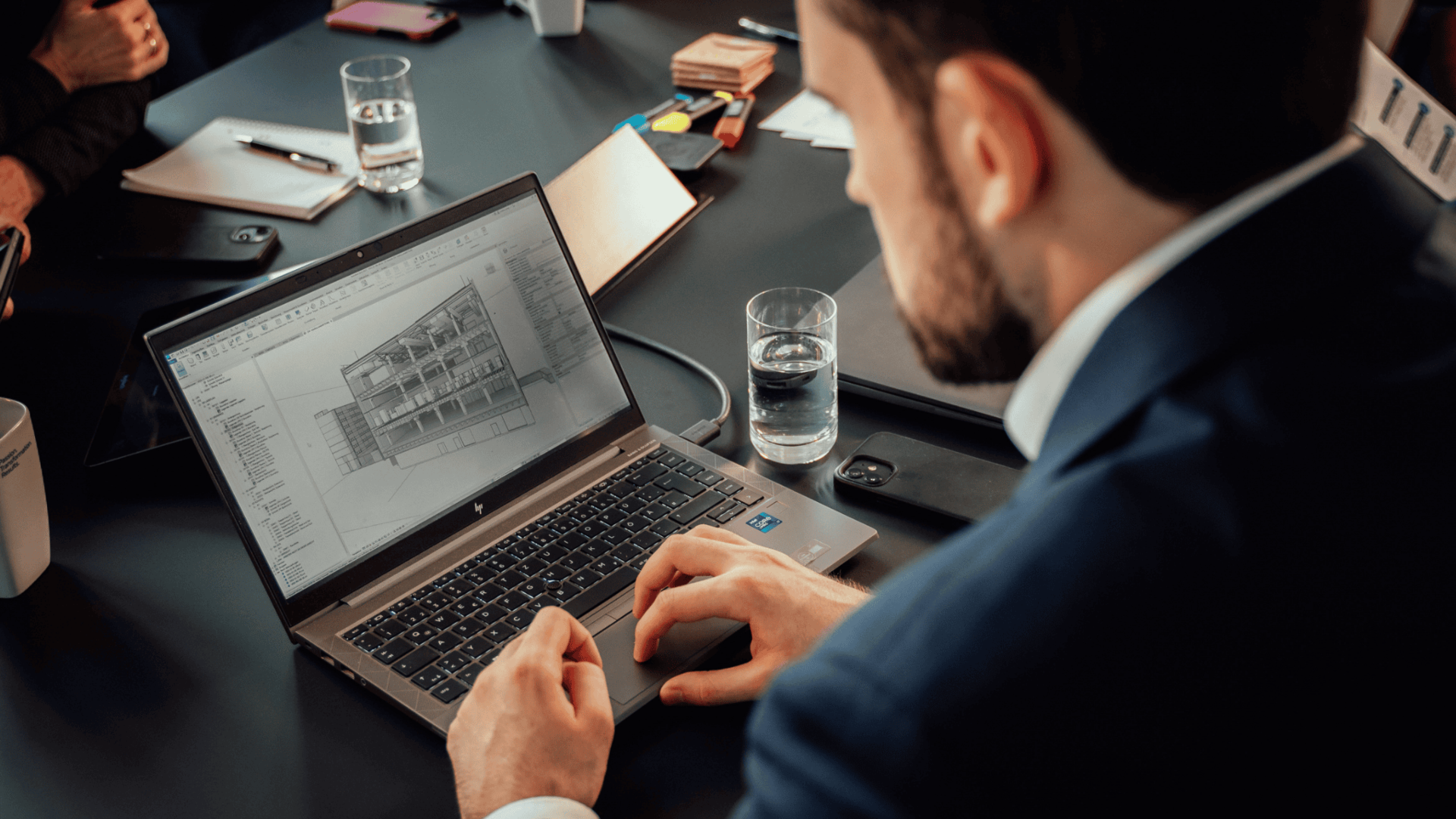 Mitarbeiter sitzt vor einem Laptop in einem Meetingraum und schaut auf eine Skizze.