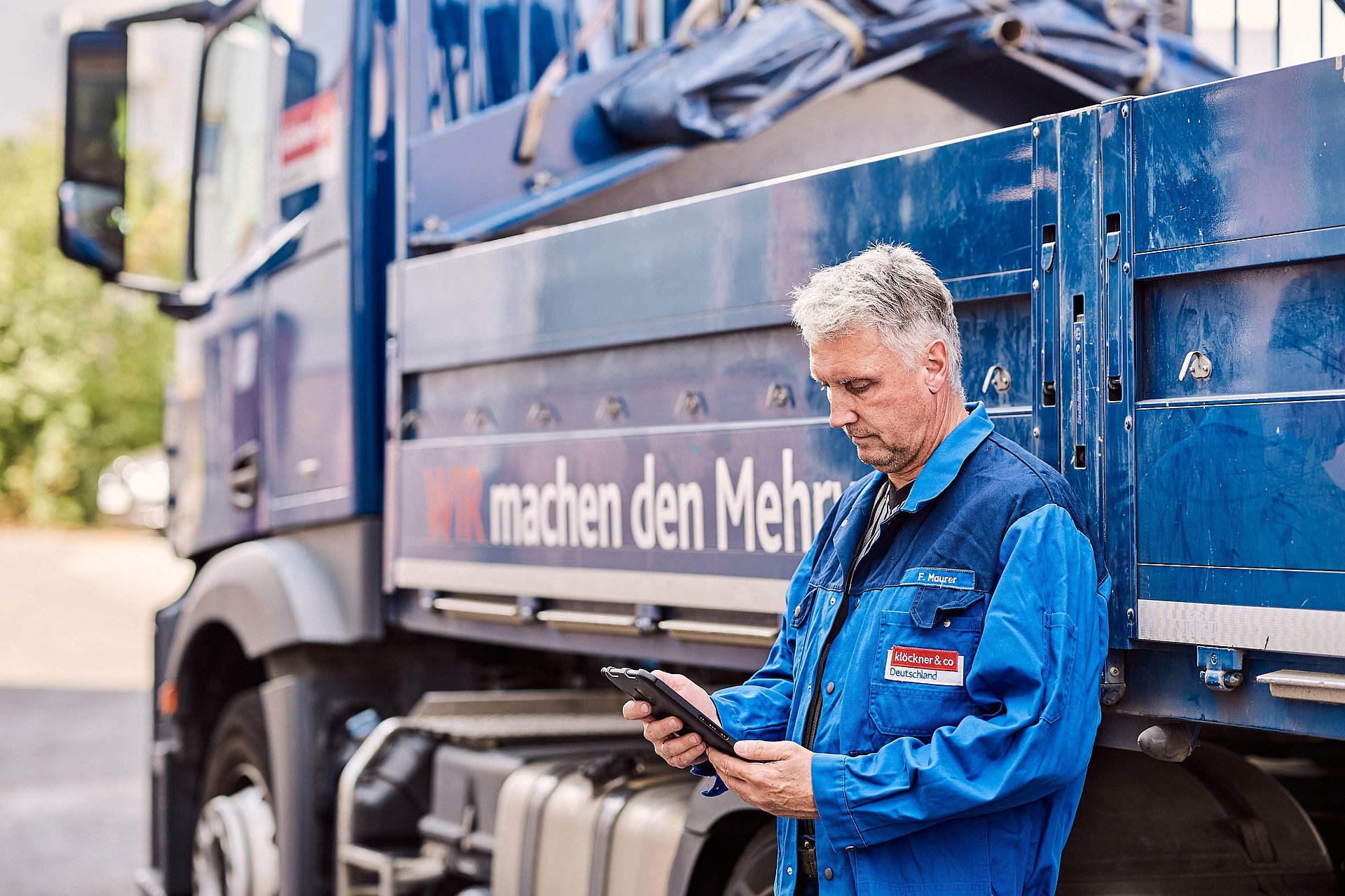 Man with tablet leans against truck