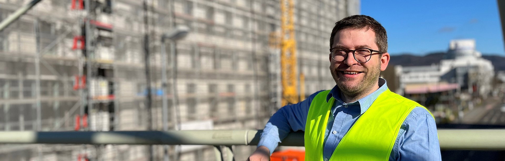 Markus Seidel stands in front of a construction project in io construction work vest