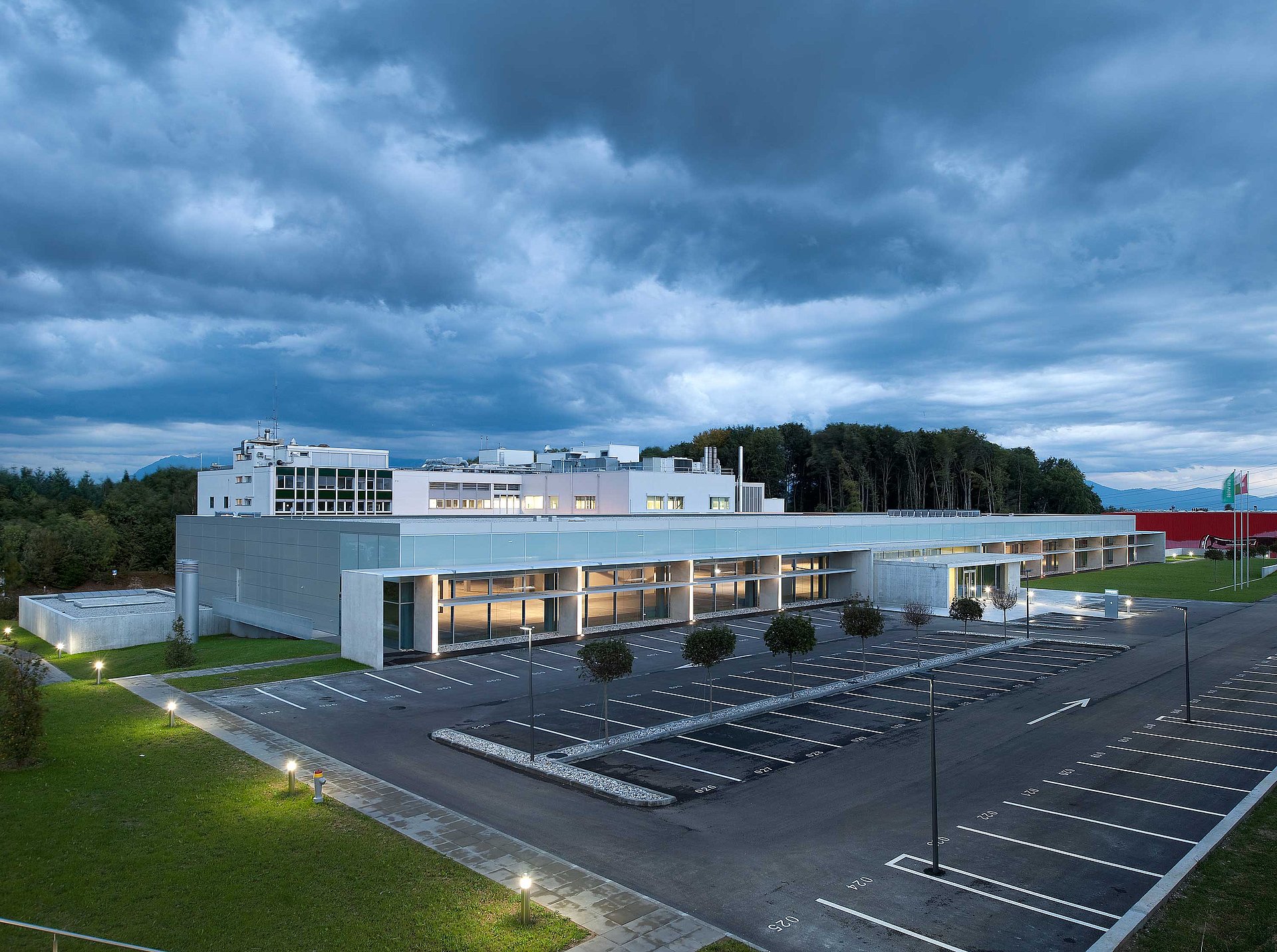 Illuminated manufacturing plant with parking lot in Crissier